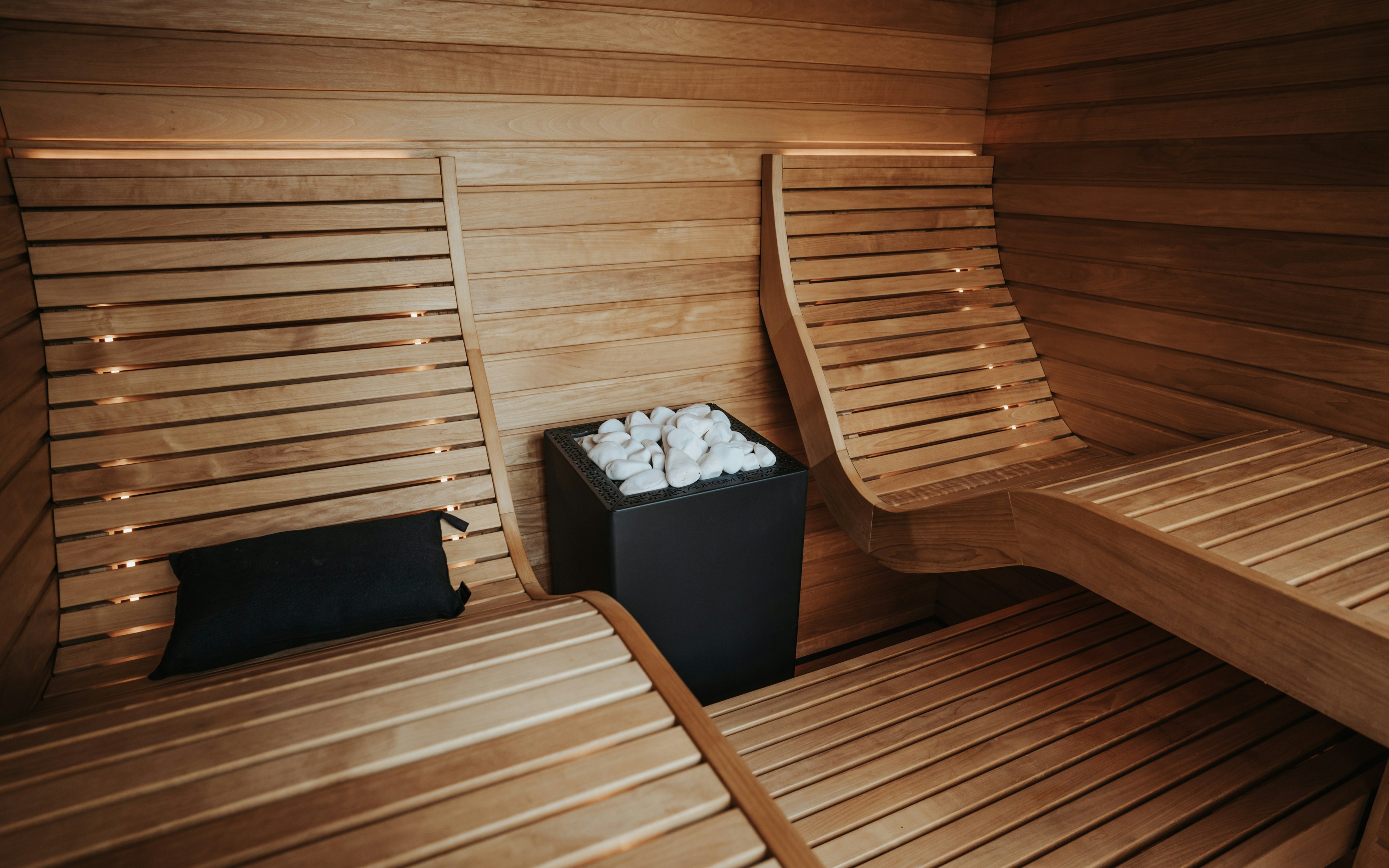 Modern wooden sauna interior with benches and a stove, designed for relaxation and skin rejuvenation