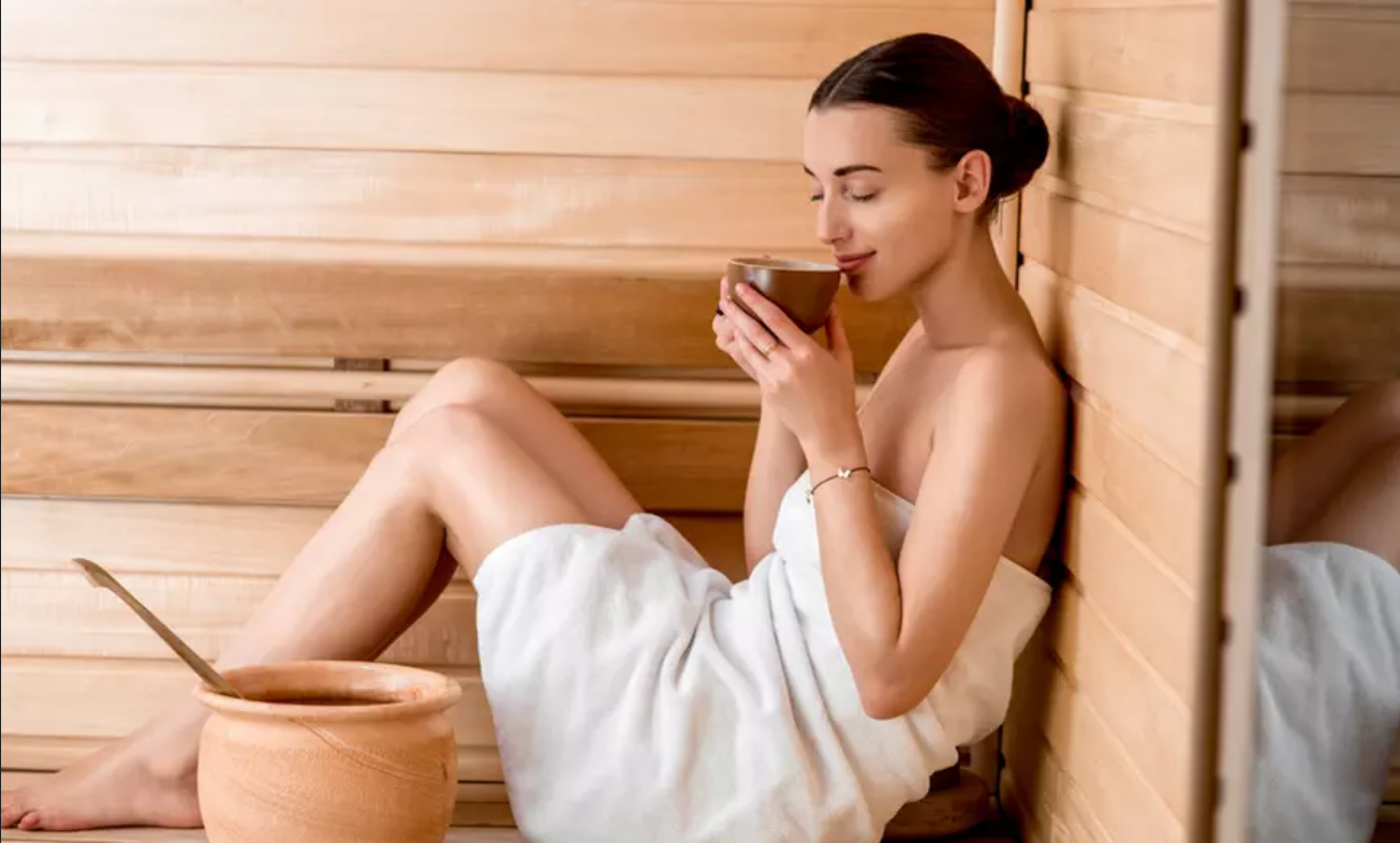 A woman drinks tea in a sauna