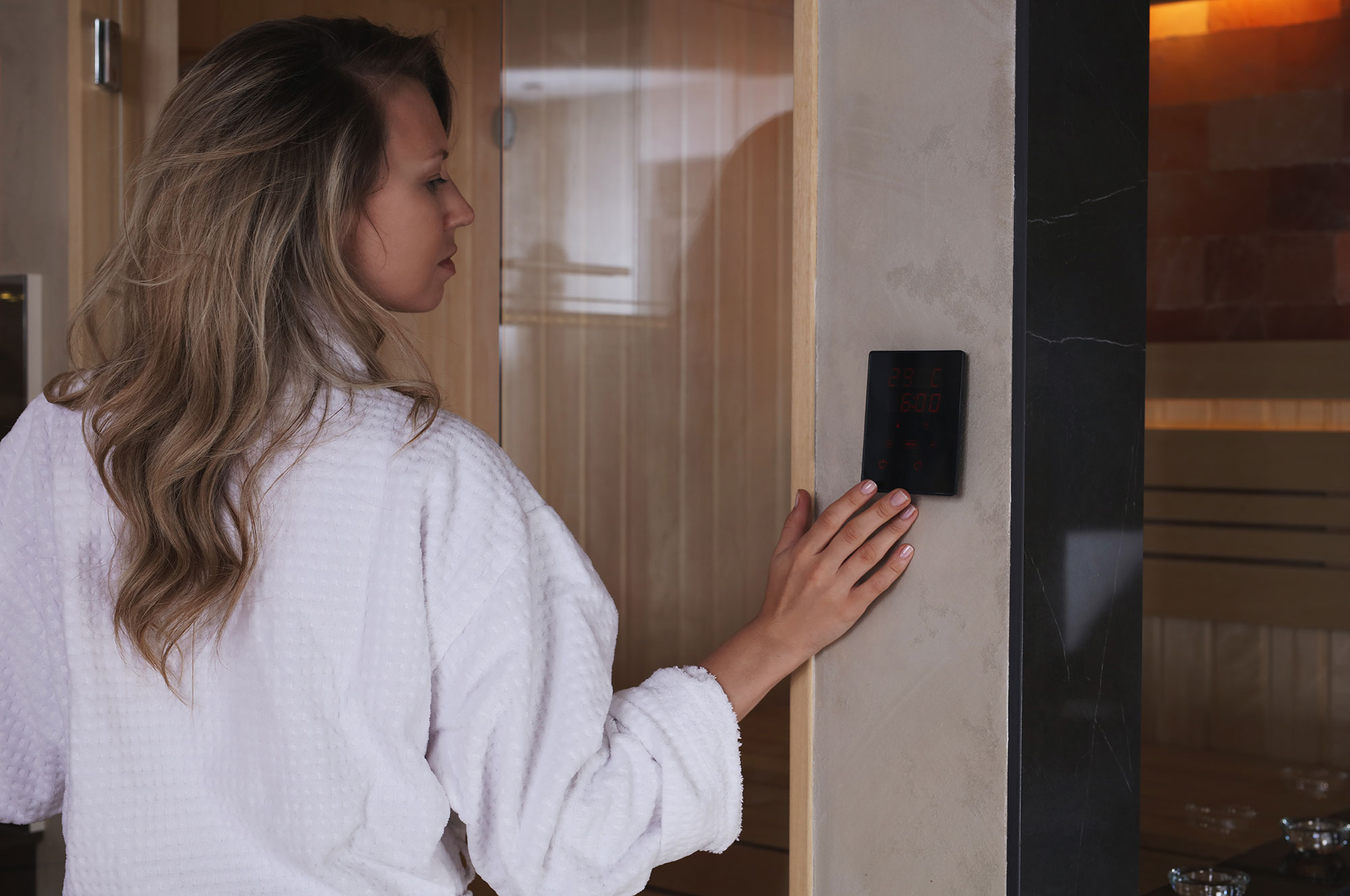 a woman adjusts the sauna control panel