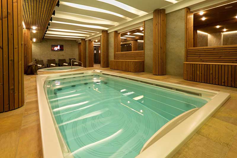 Indoor USSPA swim spa installed in a wellness area with a separate relaxation zone