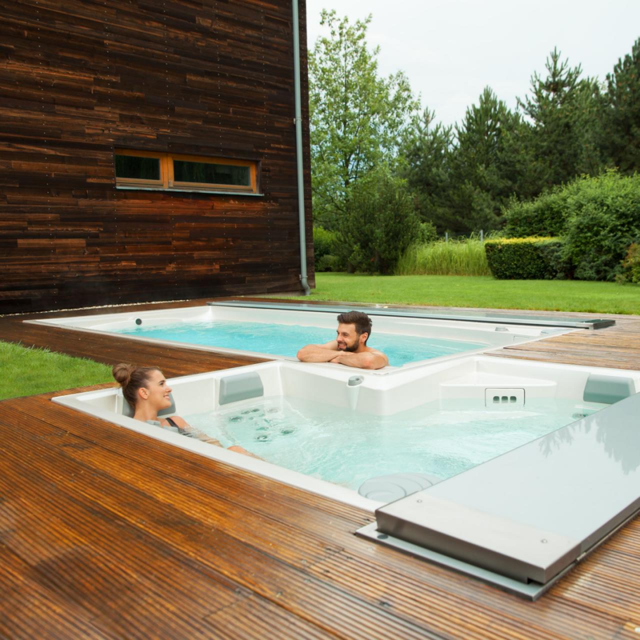 Couple relaxing in outdoor USSPA spa and swim spa pools installed on a wooden terrace