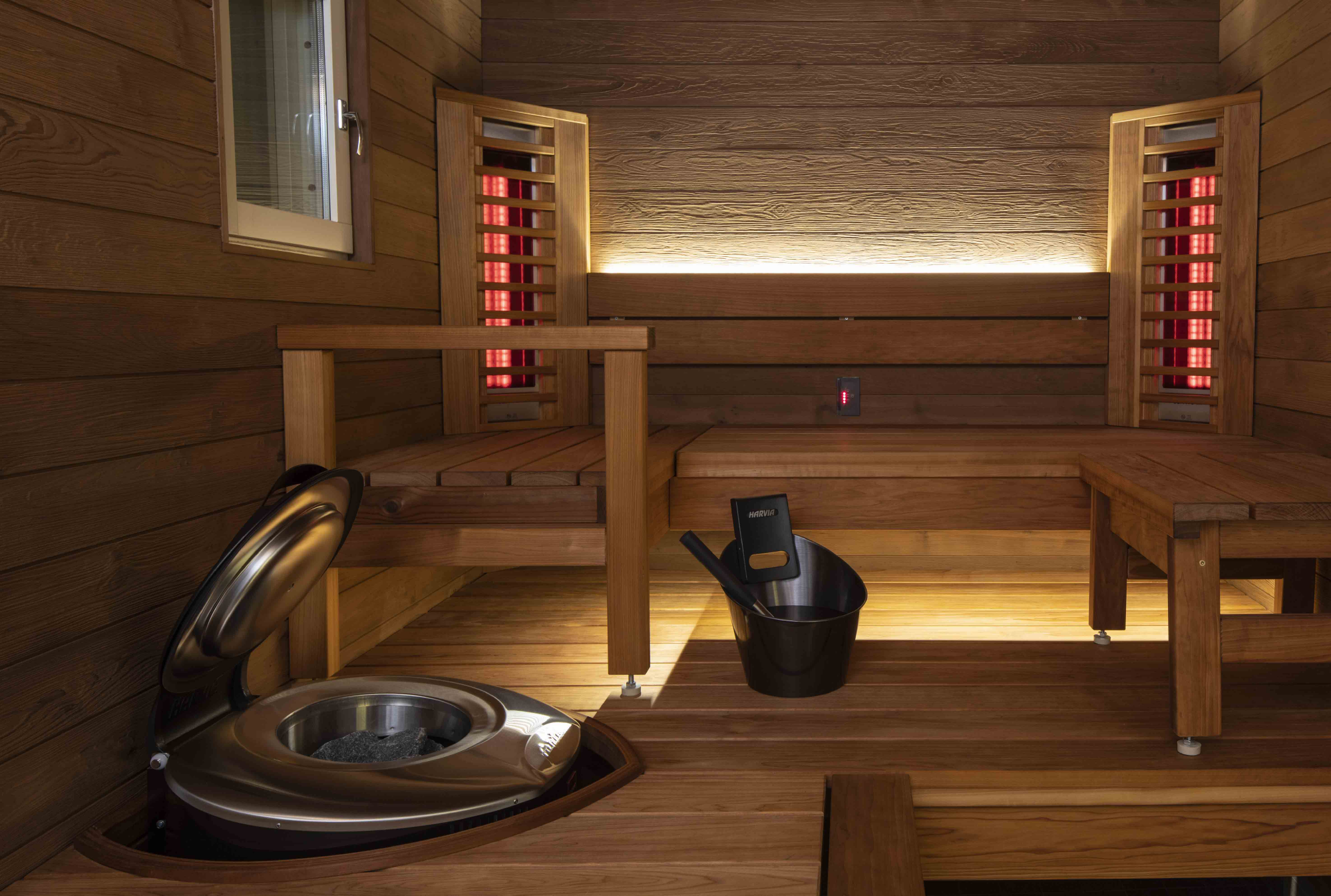 Infrared sauna interior with wooden benches, heating elements, and a stove for relaxation and wellness
